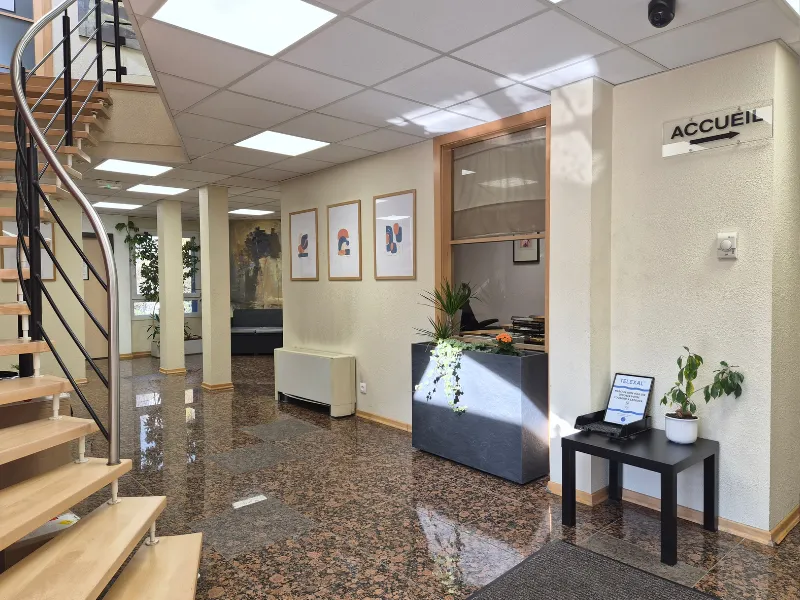 Hall d'accueil lumineux du centre d'affaires avec un sol en marbre poli, un escalier en bois et un espace de réception.