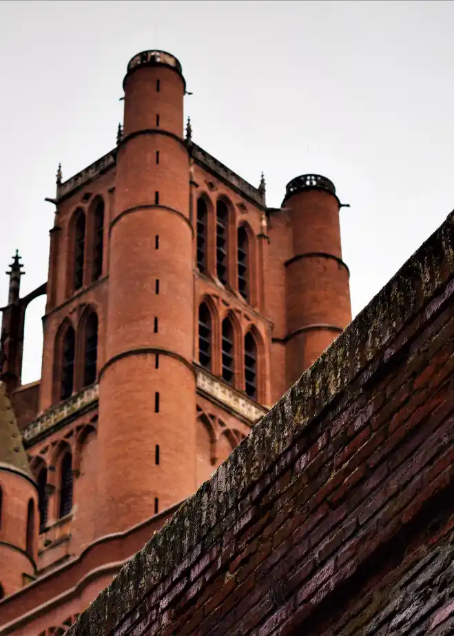 Gros plan en contre-plongée sur l'architecture défensive et les briques foraines de la Cathédrale d'Albi.