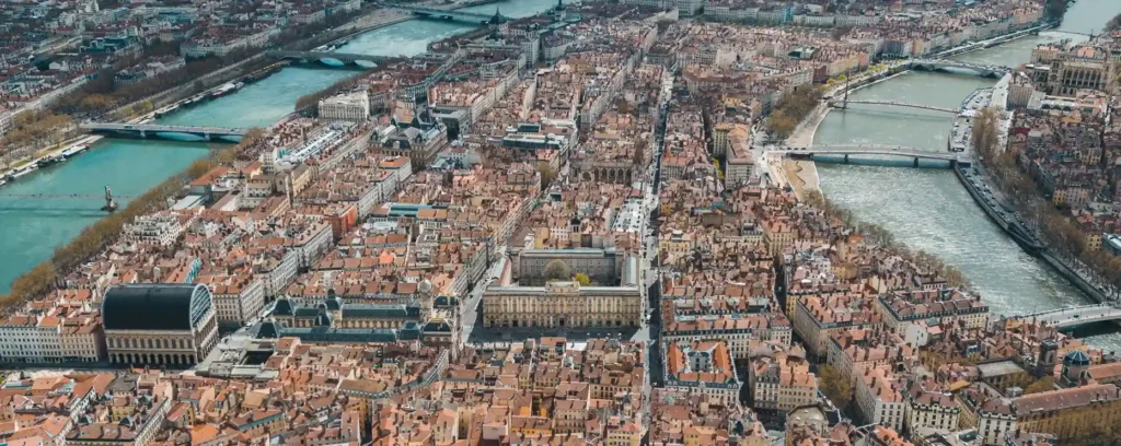 Vue aérienne panoramique de Lyon montrant la confluence de la Saône, le quartier du Vieux Lyon au pied de la colline de Fourvière et la basilique dominant la ville.