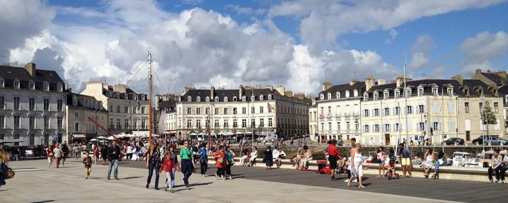 Strollers on the lively esplanade of the Vannes marina, facing the historic buildings and terraces of Place Gambetta.