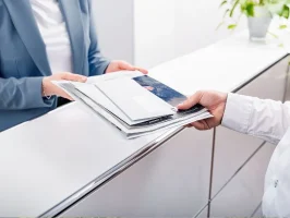 Accueil client au Business Campus Mainz : réceptionniste remettant des documents professionnels à un visiteur.