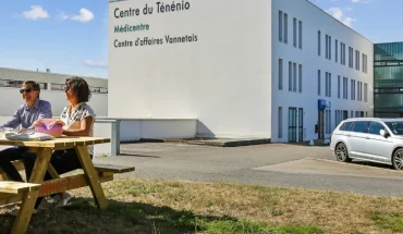 Façade du centre BURO Club Vannes Ténénio : immeuble blanc aux enseignes Centre du Ténénio et Centre d'affaires Vannetais ; deux personnes à une table de pique-nique sur la pelouse.