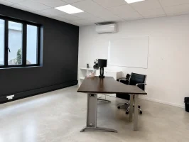 Bureau privatif spacieux au BURO Club Partner Beaune avec mur d'accent noir, bureau de direction en bois foncé et sol en béton ciré.