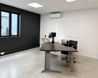 Bureau privatif spacieux au BURO Club Partner Beaune avec mur d'accent noir, bureau de direction en bois foncé et sol en béton ciré.