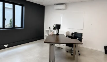 Bureau privatif spacieux au BURO Club Partner Beaune avec mur d'accent noir, bureau de direction en bois foncé et sol en béton ciré.