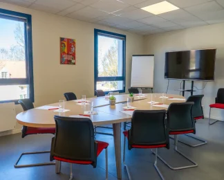 Salle de réunion avec table ovale, écran TV et paperboard au BURO Club Le Mans