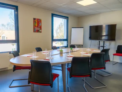 Salle de réunion avec table ovale, écran TV et paperboard au BURO Club Le Mans