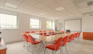 Espace de travail collaboratif et salle de séminaire spacieuse avec lumière naturelle et mobilier modulable.