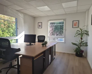 Bureau privatif lumineux et entièrement meublé avec deux postes de travail, chaises ergonomiques et vue sur la verdure.