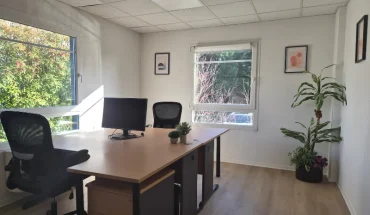 Bureau privatif lumineux et entièrement meublé avec deux postes de travail, chaises ergonomiques et vue sur la verdure.
