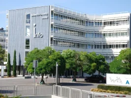 Façade extérieure du bâtiment moderne du Business Campus Mainz, arborant le logo « Info » sur une structure architecturale contemporaine entourée d'arbres.