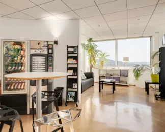 Espace détente lumineux avec distributeurs et coin salon au centre d'affaires BURO Club Nancy