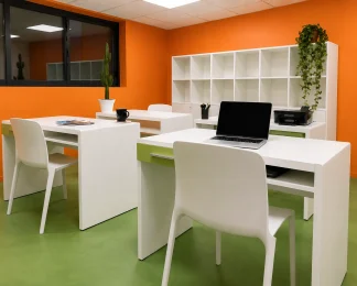 Espace de coworking au BURO Club Partner Beaune avec murs orange, sol vert, postes de travail blancs individuels et rangements.