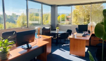 Bureau d'angle pour 3 personnes avec grandes baies vitrées, table de réunion et vue sur la verdure