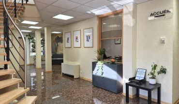 Hall d'accueil lumineux du centre d'affaires avec un sol en marbre poli, un escalier en bois et un espace de réception.