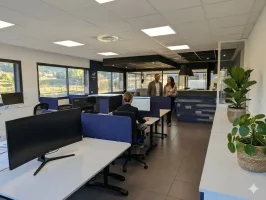 Espace de coworking moderne à Aix-en-Provence Éguilles avec bureaux partagés, séparateurs acoustiques bleus et zone d'accueil.