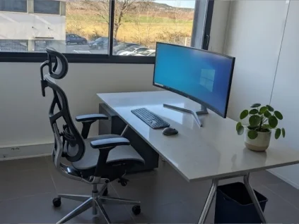 Poste de travail ergonomique chez BURO Club Partner Aix Éguilles avec fauteuil de bureau haut de gamme, écran incurvé et vue dégagée.
