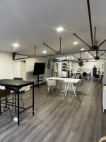 Espace de coworking ouvert et lumineux au BURO Club Partner Poitiers, équipé de bureaux partagés, table haute et écran de présentation.