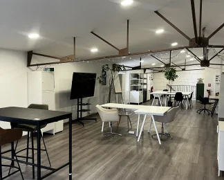 Espace de coworking ouvert et lumineux au BURO Club Partner Poitiers, équipé de bureaux partagés, table haute et écran de présentation.