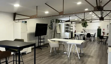 Espace de coworking ouvert et lumineux au BURO Club Partner Poitiers, équipé de bureaux partagés, table haute et écran de présentation.