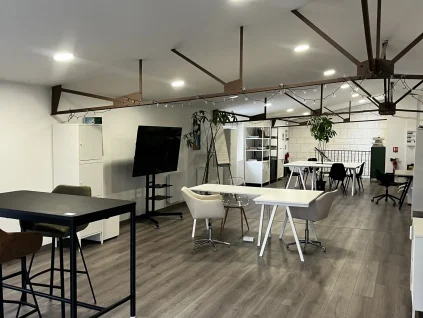 Espace de coworking ouvert et lumineux au BURO Club Partner Poitiers, équipé de bureaux partagés, table haute et écran de présentation.