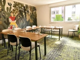 Perspective de la Loge Diego au BURO Club Partner Dijon Centre, une salle de réunion lumineuse avec moquette verte, table en bois disposée en U, et mur décoré d'une fresque mexicaine colorée type Frida Kahlo.