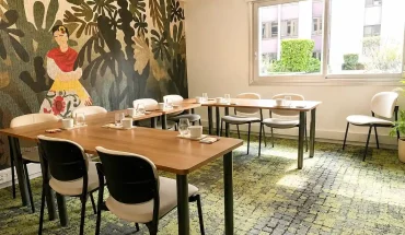 Perspective de la Loge Diego au BURO Club Partner Dijon Centre, une salle de réunion lumineuse avec moquette verte, table en bois disposée en U, et mur décoré d'une fresque mexicaine colorée type Frida Kahlo.