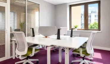 Espace de travail partagé Mexico au BURO Club Partner Dijon Centre, présentant un open space vibrant avec moquette violette, îlots de bureaux blancs, chaises ergonomiques blanches et vertes, et séparateurs acoustiques gris.