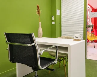 Bureau individuel au BURO Club Partner Beaune avec mur vert, bureau blanc, chaise ergonomique et décoration soignée.