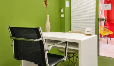 Bureau individuel au BURO Club Partner Beaune avec mur vert, bureau blanc, chaise ergonomique et décoration soignée.