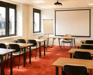 Vue de la salle Zanzibar au BURO Club Partner Dijon Centre, une grande salle de formation lumineuse avec moquette rouge, rangées de tables individuelles en bois et chaises noires, paperboard et grand écran de projection au fond.