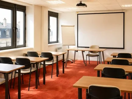 Vue de la salle Zanzibar au BURO Club Partner Dijon Centre, une grande salle de formation lumineuse avec moquette rouge, rangées de tables individuelles en bois et chaises noires, paperboard et grand écran de projection au fond.